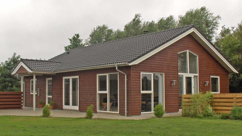 Rødt feriehus i grønne omgivelser