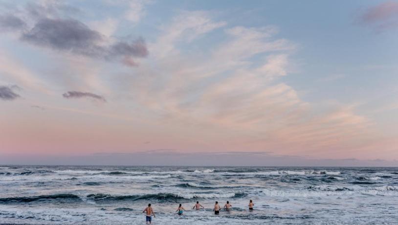 Mennesker vinterbader i Vesterhavet til solnedgang