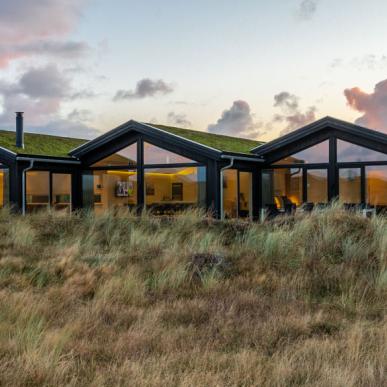 Tre sorte feriehuse med solnedgang i baggrunden