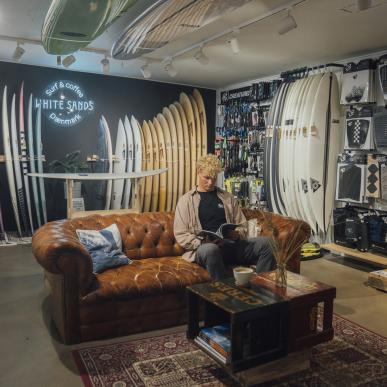 Mand sidder i surfbutik og læser magasin